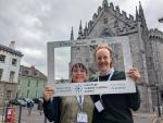 The image shows two people smiling and posing for a photo in front of a historic building at the European Carbon Farming Summit in Dublin, Ireland. They are holding a branded photo frame with the event details: 'European Carbon Farming Summit, From theory to practice, Dublin, Ireland, 4-6 March 2025.' The background features a stone building with gothic architecture.