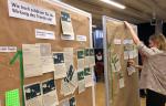 Das Bild zeigt eine Gruppenarbeitssitzung, bei der die Teilnehmer Trends an einer mit braunem Papier bedeckten Wand bewerten. Das Plakat an der Wand fragt: „Wie hoch schätzt du die Auswirkungen des Trends ein?“ Verschiedene gedruckte Materialien sind mit grünen Stecknadeln befestigt, die jeweils mit Themen wie Klimaschutz, Anpassung, Resilienz, nachhaltige Landwirtschaft und regionale Wertschöpfungsketten beschriftet sind. Eine Person passt die Materialien an der Tafel an.