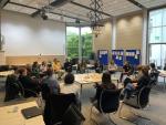 Participants in a workshop sit in a circle in a bright conference room, discussing urban nature and sustainable urban development.